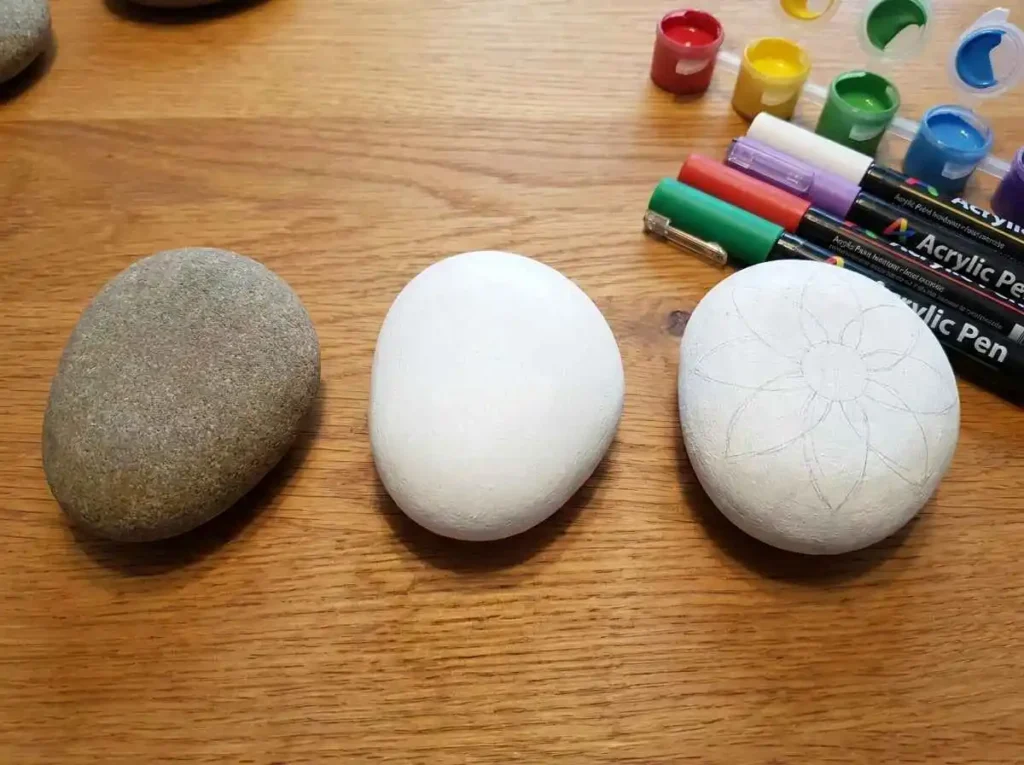 Applying a white base coat to a rock before painting designs