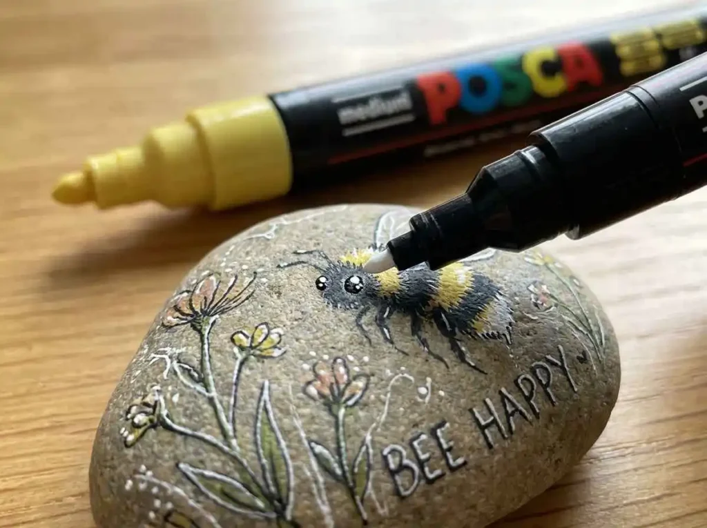 Fine tip paint pen adding small details to a painted rock