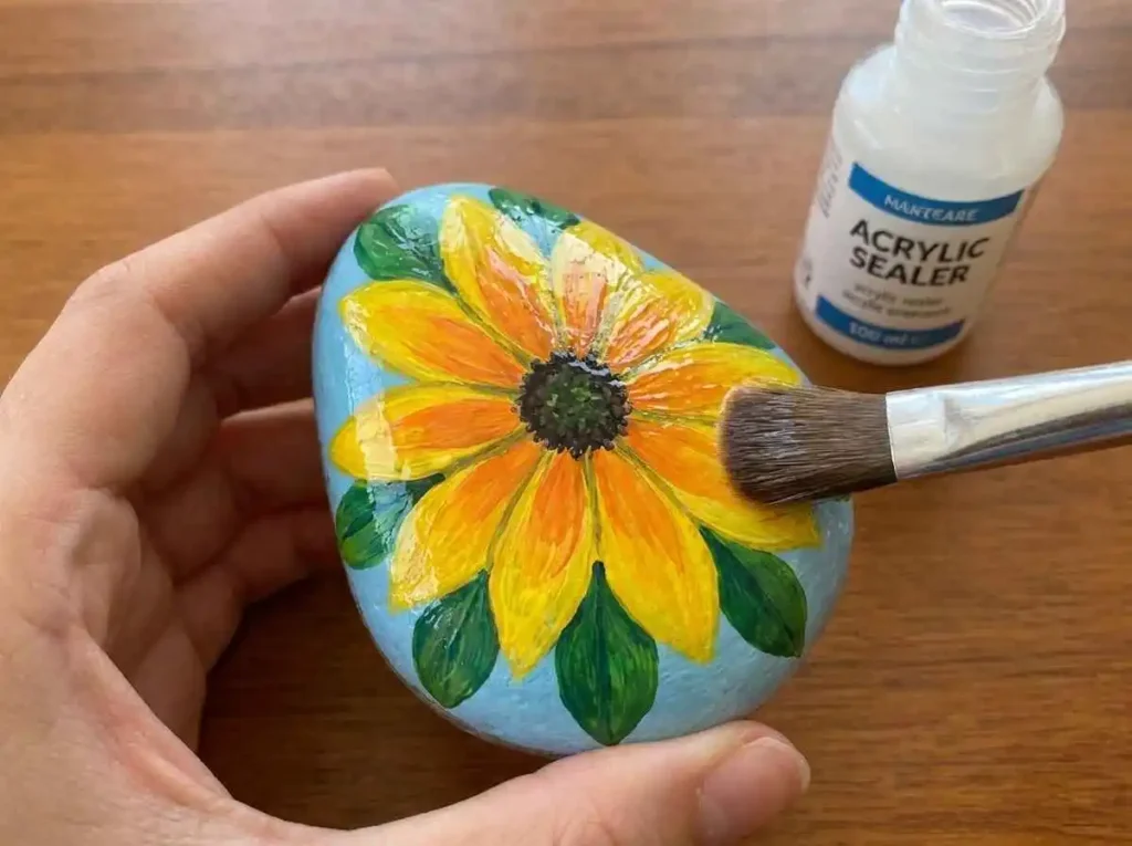 Applying protective sealer to a finished painted rock