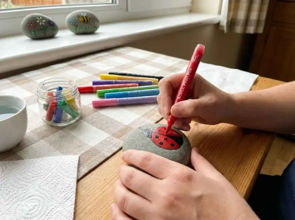 Beginner using acrylic paint pens to decorate a smooth rock